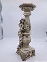 Front view of cast resin pedestal showing female figure, column, and top platform