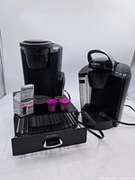 Front view of both Keurig brewers, storage drawer, filters, filter kit box