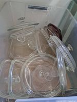 Multiple glass lids inside storage bin showing quantity and variety