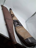 Two long brown leatherette firearm cases side by side