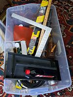 Full tote showing mix of rulers, mitre box, oil bottle, brushes, cable and other items