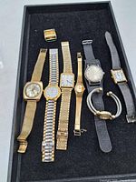 Tray overview showing seven wrist watches, empty Hamilton case and bracelet