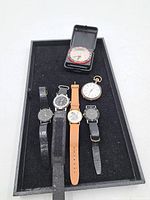 Overall view of tray with pocket watch, travel-case watch and five wristwatches