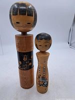Both kokeshi dolls standing side by side showing relative sizes and full bodies