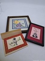 Three framed cross-stitch pieces grouped together