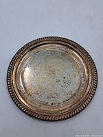 Front view of silver-plated tray showing rope border and wear