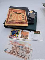 Overview of album, binder, stamp sheet, FDC and two banknotes
