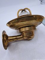 Side view of brass sconce showing flange, arm, shade, glass globe and cage