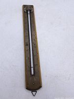 Full view of brass wall thermometer, dual scales visible