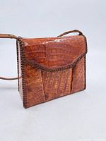 Front view of brown cognac leather shoulder bag with flap and whipstitch trim