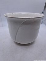 side view of white glazed planter showing swirl relief and flared rim
