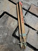 Tripod folded, full view showing red lettering and leather strap