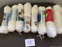 Eight white yarn skeins lined up showing full lot