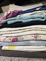 Stack of assorted sheets, crochet cover and linens