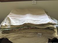 Stack of folded bedding showing various sheets, covers and comforter