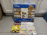Front view of sealed Disney sticker pack with two loose sticker sheets displayed