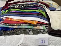 Full stack of assorted fabric pieces on bed