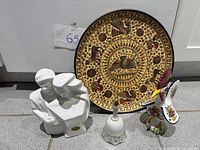 Group shot showing all four items: couple statue, Greek plate, bell, rooster figurine