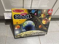 Front view of sealed Melissa & Doug Solar System Floor Puzzle showing artwork and 48 jumbo pieces note