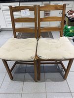 Front view of two wooden chairs with cushions attached