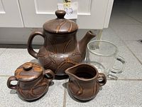 Front view showing teapot, creamer, sugar bowl with lid, and clear mug