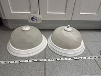 Both ceiling fixtures side by side with tape measure indicating diameter