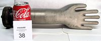 Side view of metal glove mold with Coca-Cola can for scale, shows entire length and base flange