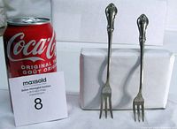Both forks standing beside cola can for scale