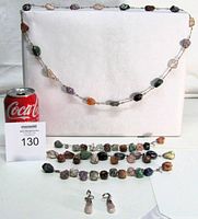 Entire set with soda can for scale: necklace draped, three bracelets, earrings