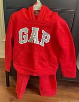 Front view of red GAP hoodie and sweatpants on hanger