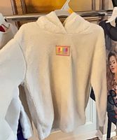 White Sherpa fleece hoodie with Puma patch hanging on rack