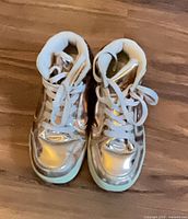 Top view of both sneakers showing metallic gold uppers and white laces