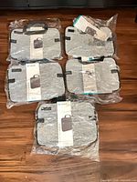 Five individually packaged gray Speck Station Pro laptop sleeves displayed on wood floor