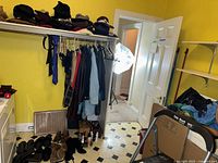 Full closet view showing hats on upper shelf, coats on rail, scarves, footwear at floor, shoe care items