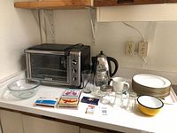 Overall lot on countertop showing toaster oven, kettle, plates, glassware, playing cards