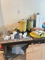overall view of table with coffee urns, mugs, glasses, linens