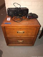 Front view of night table with boombox and clock radio on top