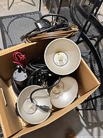 Box containing four black metal dome lamps with cords