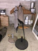 two folded umbrellas and two bases on garage floor