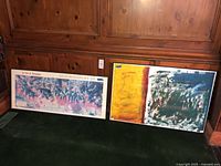 Both framed artworks leaning against wood paneling