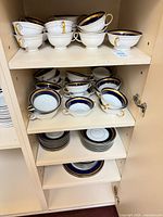 Cabinet shelves holding grouped Rosenthal dishes