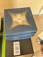 Stack of three blue boxes with window showing coasters inside