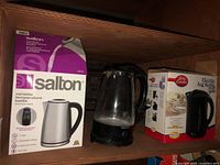 Shelf view showing boxed Salton kettle, glass Toastess kettle and boxed Betty Crocker kettle