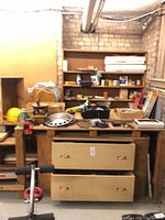 Workbench with drawers, shelving, hubcaps, hard hat, tools and hardware visible