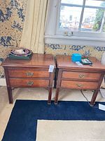 Pair of matching wooden nightstands under window