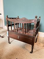 Overall view of mahogany Canterbury magazine rack showing slatted compartments, drawer, turned legs and casters