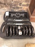 Closed plastic case opened to show dumbbell components