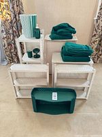 Group shot: 3 white hampers, 3 white shelves, green wicker shelf, waste bin, soap dispenser, tumbler, soap dish, towels