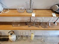 Shelves showing multiple clear glass vases and porcelain vase