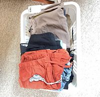 Stack of folded athletic pants and shorts in white basket